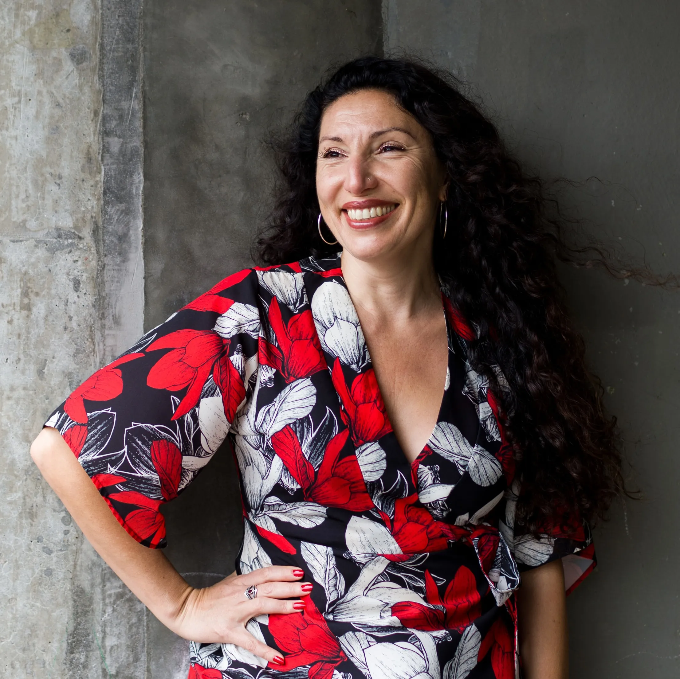 Half-body shot of Maritza Schafer leaning against a concrete wall wearing a top with white, red, and black colors